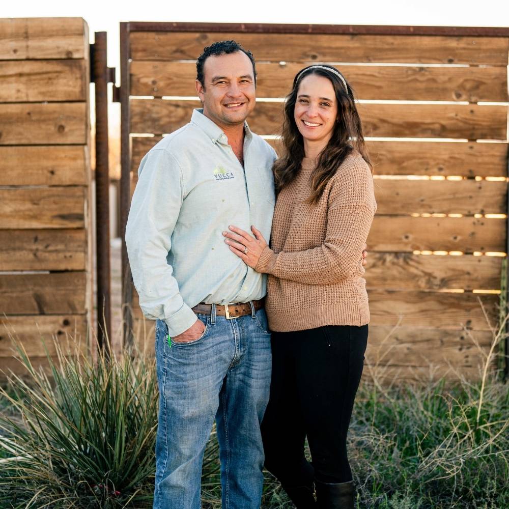 Couple smiles by wooden fence